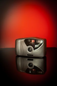 Compact camera photographed on a table in a studio against a red background