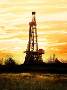 Natural gas production, land drilling rig at sunset.