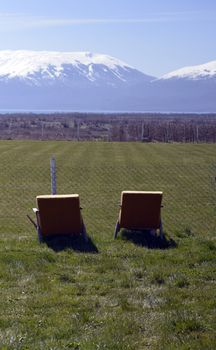 Photo Old damaged chairs on the grass beneath the village soccer field