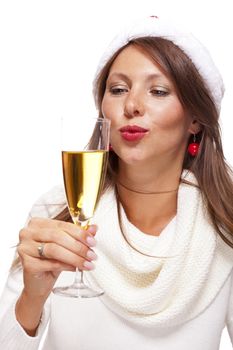 Playful woman wearing a festive red Santa hat and holding a flute of champagne celebrating Christmas blowing a kiss across the palm of her hand with a mischievous smile, on white