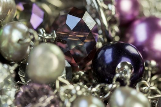 Close up of three attractive shiny purple beads attached by silver chains on an item of jewellery in a fashion and handicraft concept