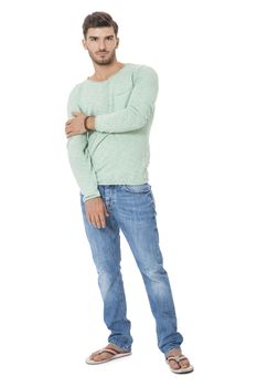 Handsome confident relaxed handsome young man with a beard posing with his hands in his pockets in jeans and slip slops, isolated on white