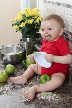 Baby boy surrounded by sprinkles in the kitchen