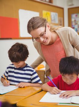 Pretty teacher helping pupil in classroom at the elementary school