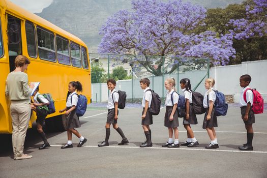 Cute schoolchildren waiting to get on school bus outside the elementary school