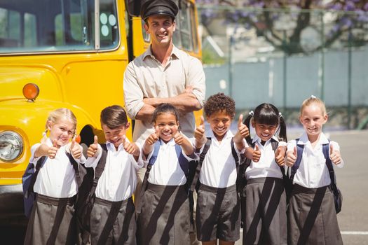 Cute pupils with their school bus driver outside the elementary school