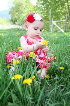 Brunette baby girl sitting outside in the field