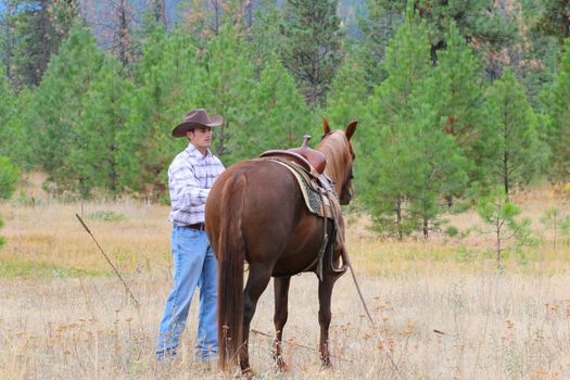Young cowboy working with his horse in the field