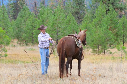 Young cowboy working with his horse in the field