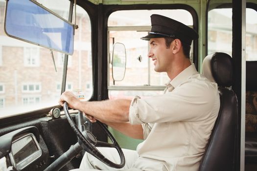 Smiling driver driving the school bus outside the elementary school