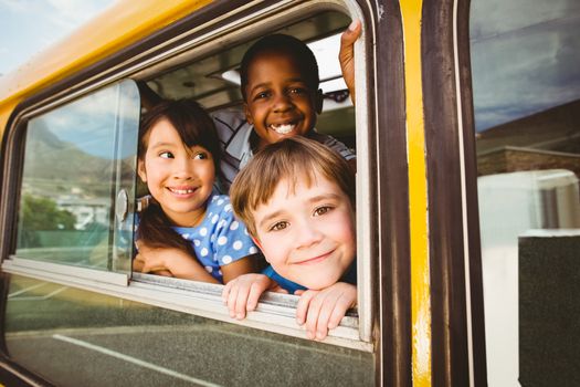 Cute pupils smiling at camera in the school bus outside the elementary school