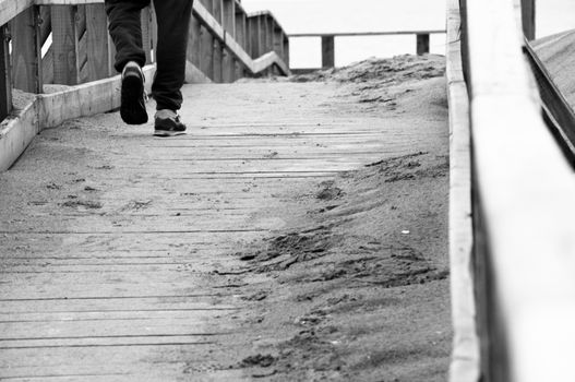 a lonely boy walking on a wooden bridge near the sea