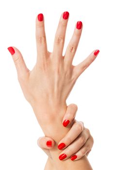 Woman with beautiful manicured red fingernails gracefully crossing her hands to display them to the viewer on a white background in a fashion, glamour and beauty concept