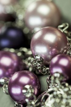 Close up of three attractive shiny purple beads attached by silver chains on an item of jewellery in a fashion and handicraft concept