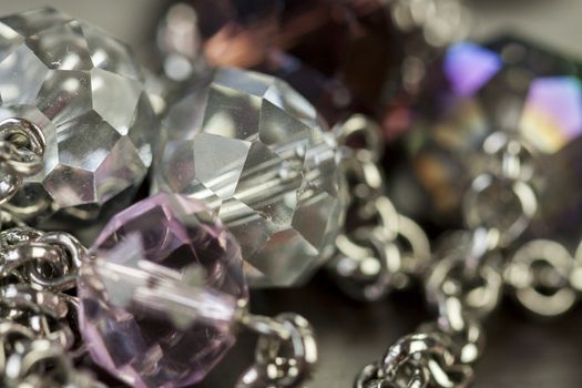 Close up of three attractive shiny purple beads attached by silver chains on an item of jewellery in a fashion and handicraft concept