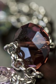 Close up of three attractive shiny purple beads attached by silver chains on an item of jewellery in a fashion and handicraft concept