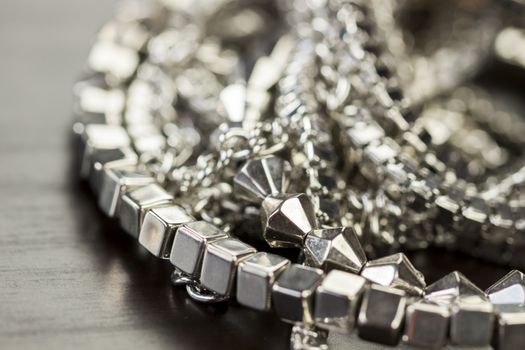 Pile of assorted silver chains with shiny box chains, cube chains and ordinary linked chain on a grey background conceptual of fashion jewellery