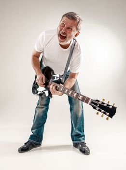 Full length portrait of a guitar player exciting music on gray background