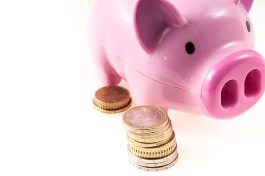 Savings represented by a pink pig with coins on white background