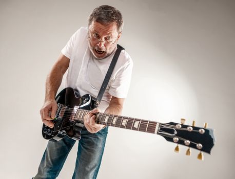 Portrait of a guitar player exciting music on gray background