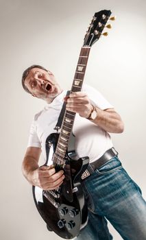 Portrait of a guitar player exciting music on gray background