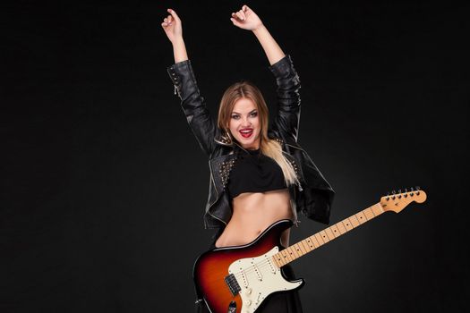 Beautiful blonde girl playing guitar in rock style on a black background