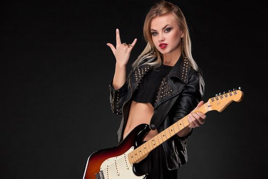 Beautiful blonde girl playing guitar in rock style on a black background