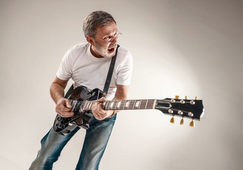 Portrait of a guitar player exciting music on gray background