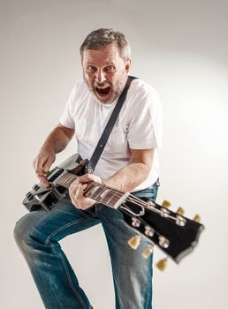 Portrait of a guitar player exciting music on gray background