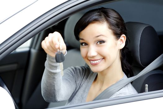 Pretty female driver in a white car showing the car key.