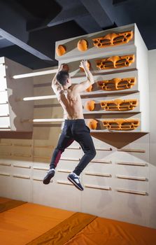 Young man practicing rock-climbing in climbing gym indoors