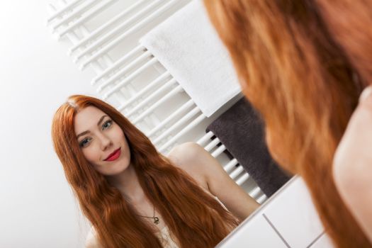 Close up Mirror Reflection of a Gorgeous Young Woman While Touching her Long Blond Hair