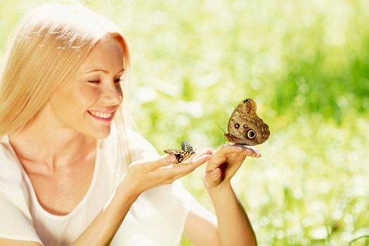 Beautiful young happy Woman playing with butterfly outdoors