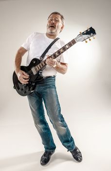 Full length portrait of a guitar player exciting music on gray background