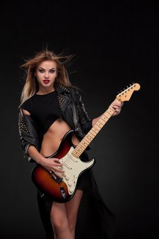 Beautiful blonde girl playing guitar in rock style on a black background