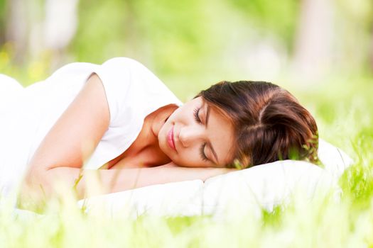 Beautiful young woman sleeping on grass outdoors