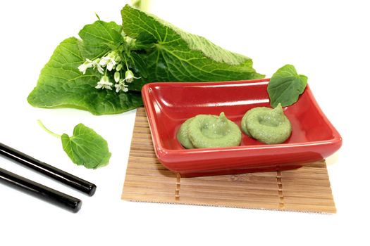 Wasabi with Chopsticks, leaves and blossoms in a red bowl