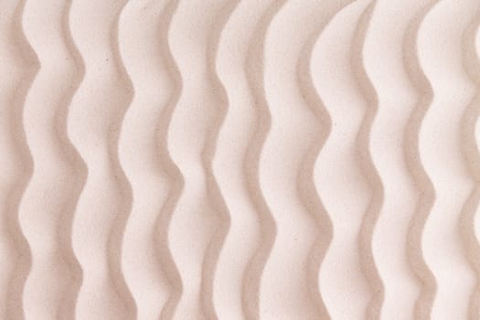Decorative patterned golden beach sand background with wavy lines reminiscent of the ripples in the sea in a nautical or marine themed concept