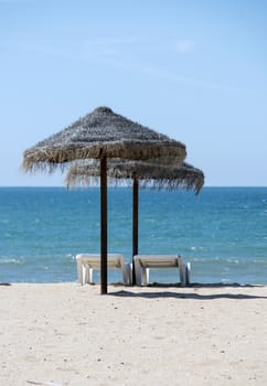 tropical parasols on the algarve beach with the sea as background