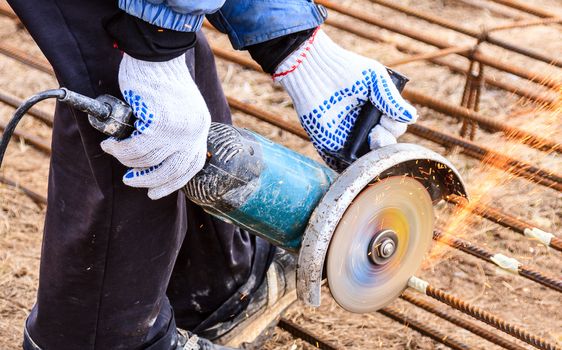 industrial worker working on cutting a metal and steel bar with angle grinder