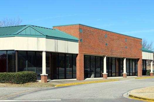 Modern strip shopping center has no tenants or stores.  This is a newer brick building with a single story.