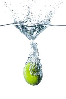 Fresh lime falling into water, isolated on white background
