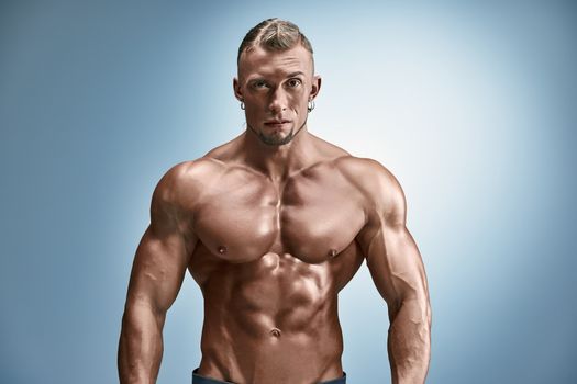 torso of attractive male body builder on blue background.