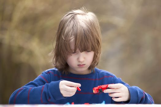 Boy Putting Together his Assembling Toys Outdoors