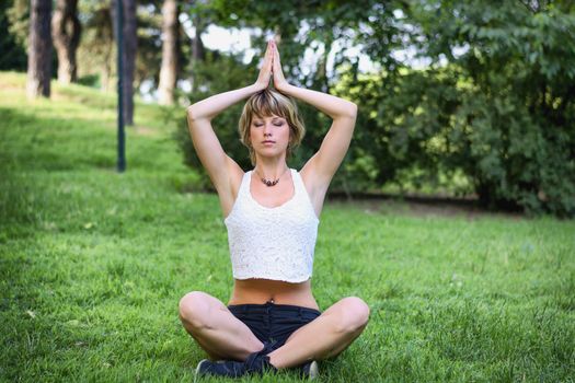 Healthy Young Pretty Woman Doing an Outdoor Yoga Exercise at the Grassy Ground Alone