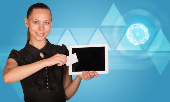 Young businesswoman holging tablet and blank card and looking at camera on abstract blue background