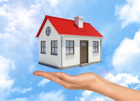 House under businesswomans hand on cloudy blue sky background 