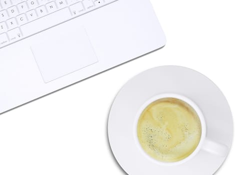 Part of white laptop and cup with coffee on plate on isolated white background, top view. Closed up