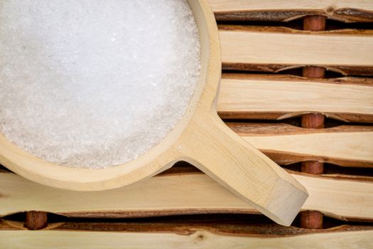 Magnesium sulfate (Epsom salts) in a rustic wooden scoop - relaxing bath concept