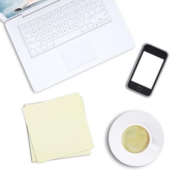 White laptop with mobile phone and coffee cup on isolated white background, top view. Closed up